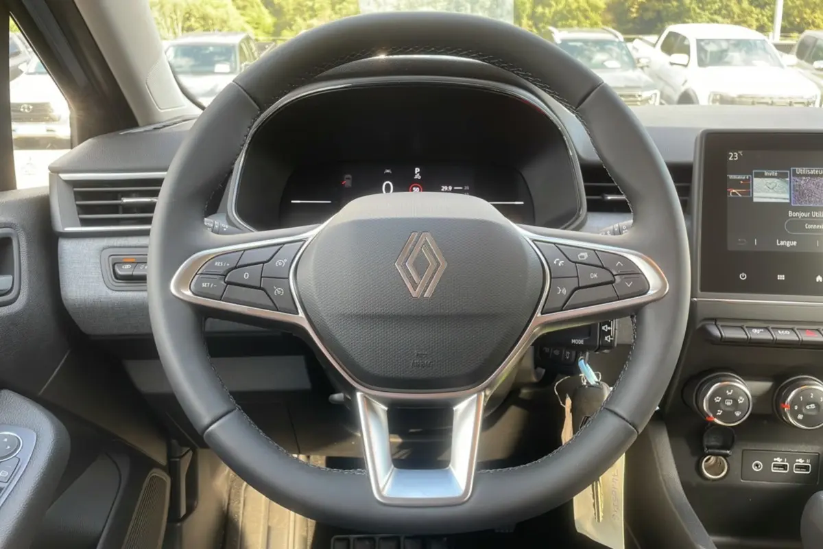 Vue intérieure centrée sur le volant multifonctions Renault Clio 2025, avec tableau de bord numérique et écran tactile.