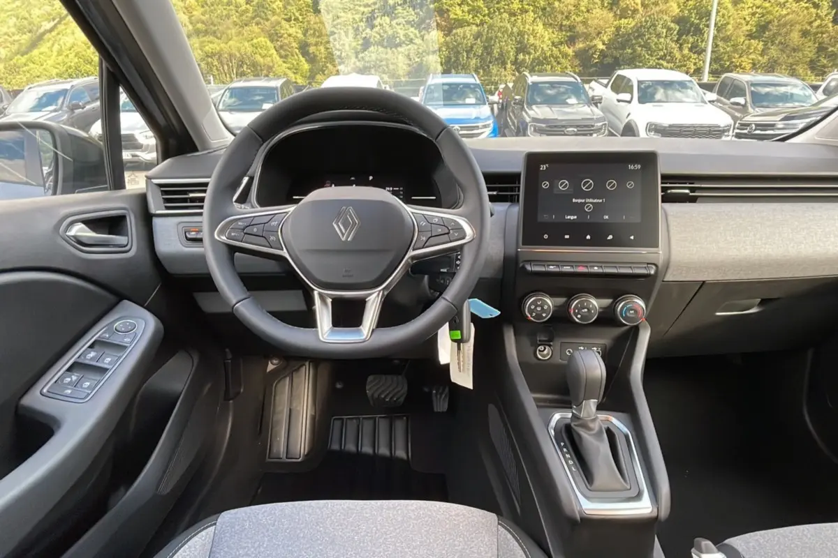 Vue intérieure avant de la Renault Clio 2025, volant multifonctions, écran tactile et levier de boîte auto visibles.