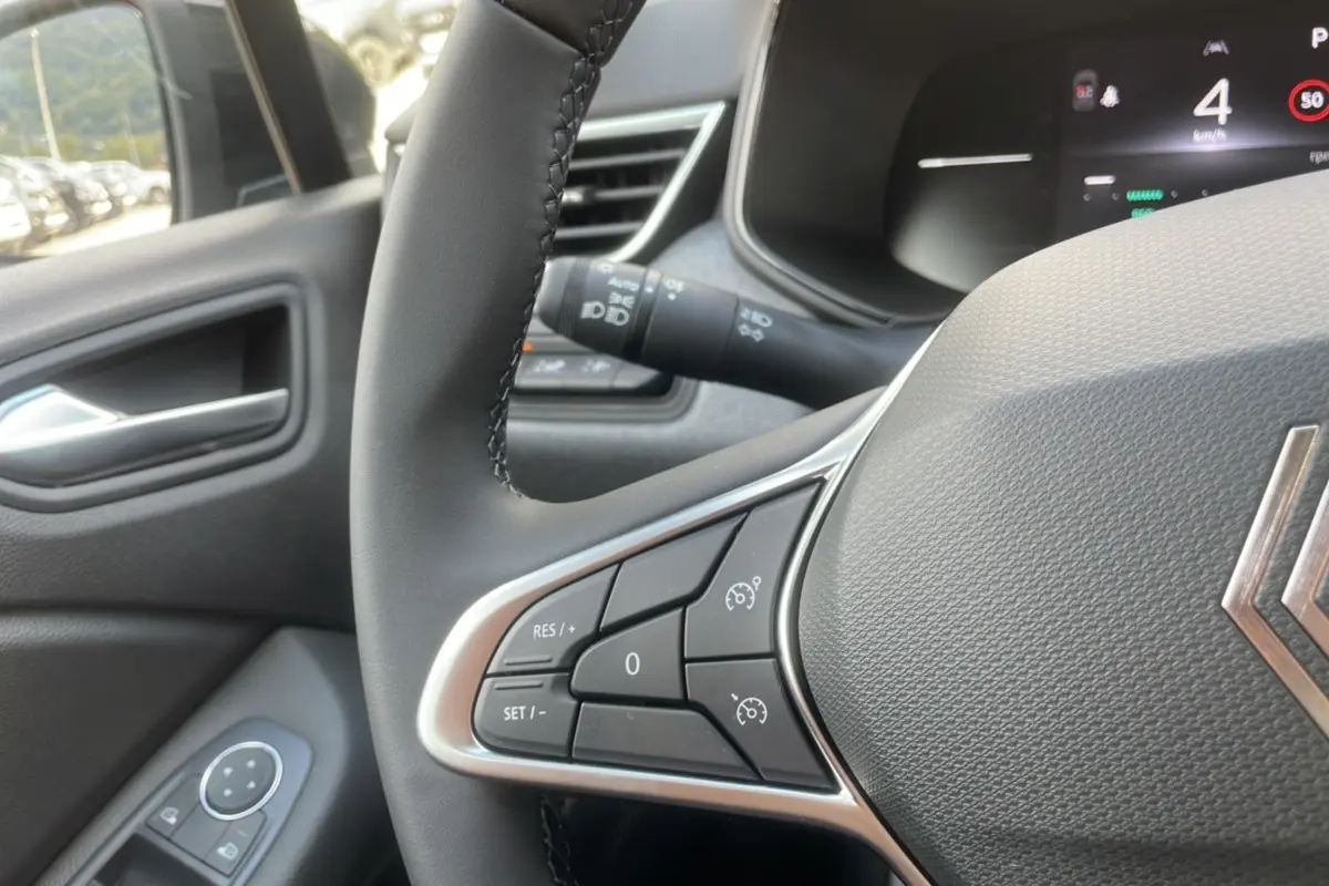Gros plan sur le volant multifonctions de la Renault Clio 2025, avec commandes de régulateur et tableau de bord numérique.