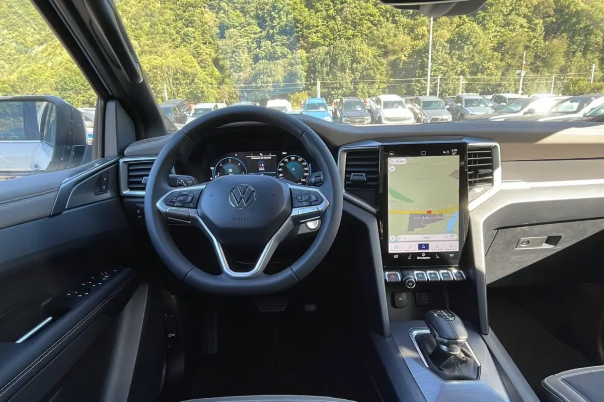 Vue intérieure avant du Volkswagen Amarok blanc 2026, volant cuir multifonctions et écran tactile vertical.