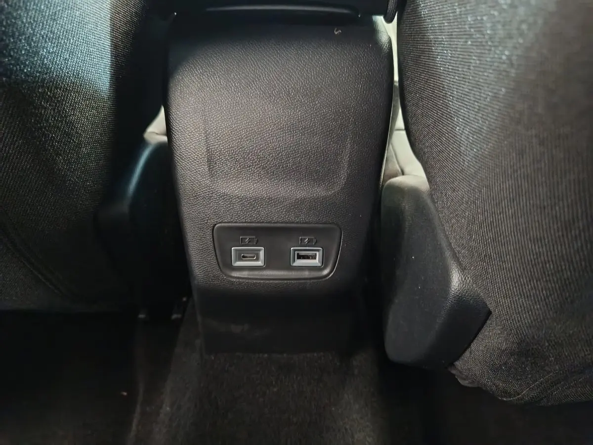 Prise USB type C et USB standard à l'arrière de la console centrale dans l'habitacle gris foncé d'une Peugeot 208 2025.