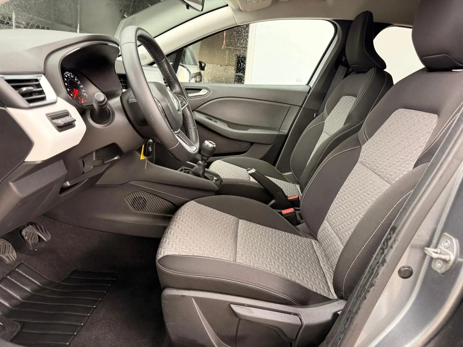 Vue intérieure avant de la Renault Clio V 1.0 TCE 90 Evolution avec tableau de bord noir et blanc et levier de vitesse manuel.