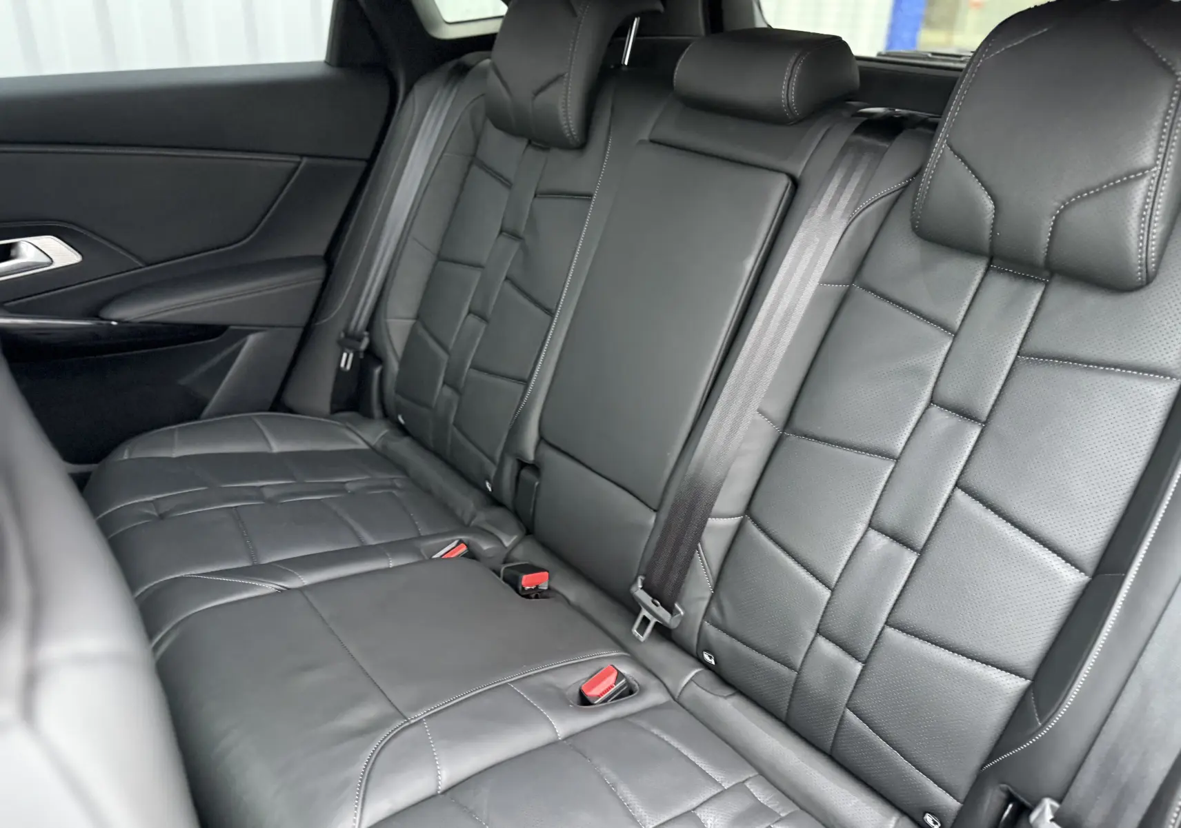 Vue intérieure des sièges arrière en cuir noir du DS7 2025, mettant en valeur les finitions et les ceintures de sécurité.