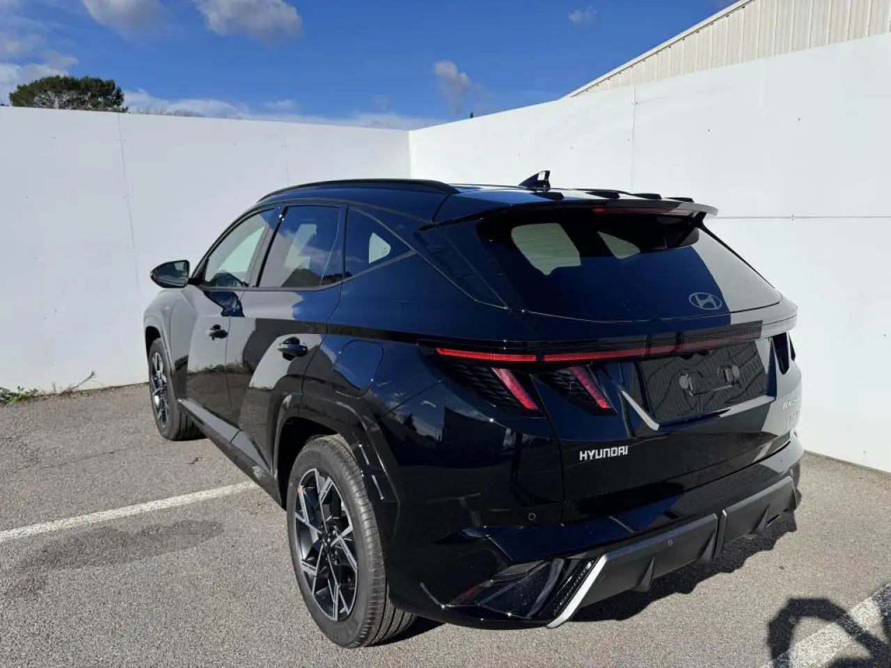 Vue 3/4 arrière droite du Hyundai Tucson noir Abyss Metal avec feux arrière LED et jantes alliage 19 pouces N Line.