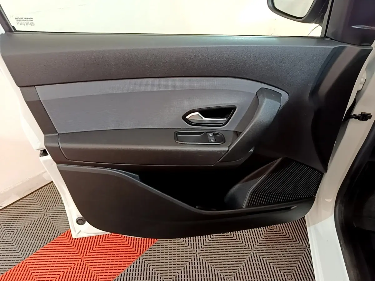 Vue intérieure de la porte avant droite noire et grise du Renault Express blanc, avec poignée et commandes de vitres.