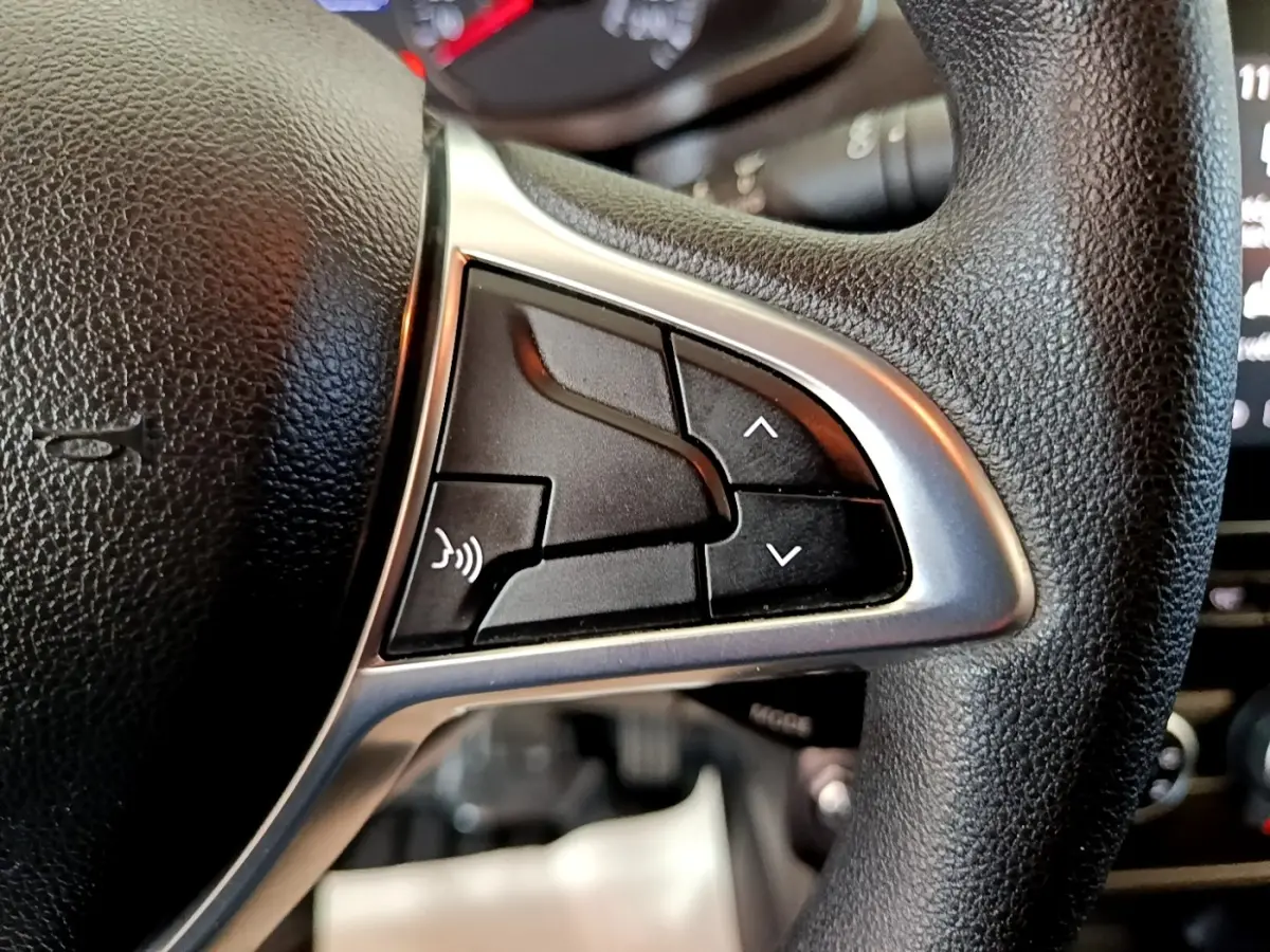 Gros plan sur les commandes gauche du volant noir du Renault Express blanc, boutons de réglage et commande vocale visibles.