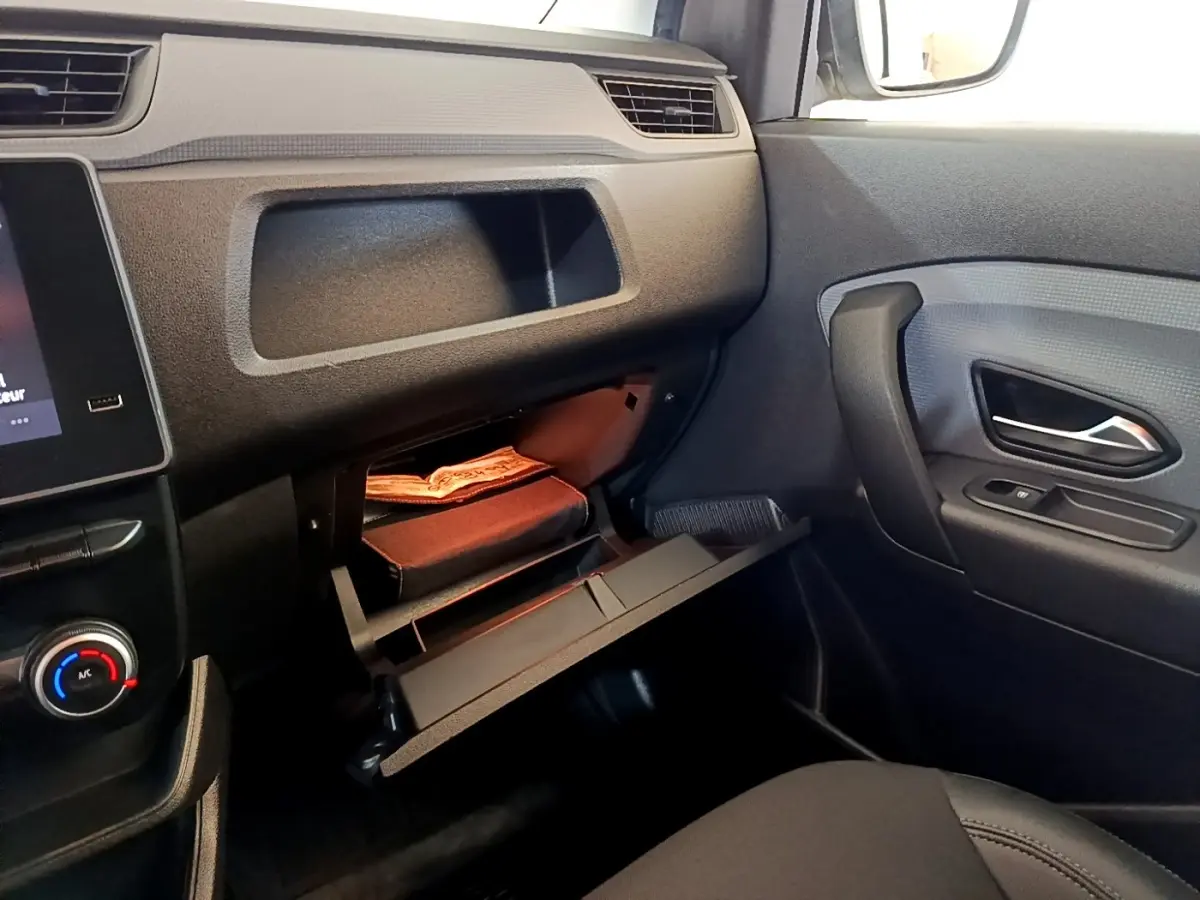Intérieur noir du Renault Express 2021, vue côté passager avec boîte à gants ouverte et porte avec poignée visible.