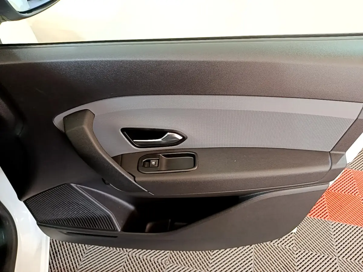 Vue rapprochée de la porte intérieure côté conducteur du Renault Express blanc, avec poignée et commande de vitre noire.