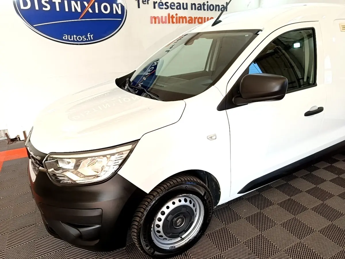 Vue 3/4 avant droit d'un Renault Express blanc avec pare-chocs noirs et jantes acier en intérieur showroom.