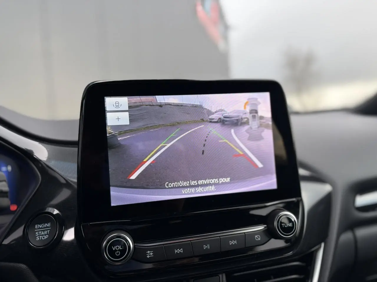 Écran tactile intérieur montrant la caméra de recul à 180° du Ford Puma gris Solar, avec commandes audio en dessous.