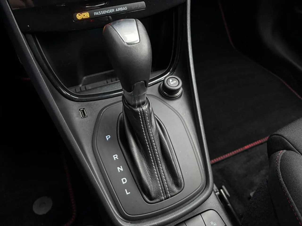 Gros plan sur la console centrale noire avec levier de vitesse automatique et surpiqûres rouges du Ford Puma Ecoboost 2023.