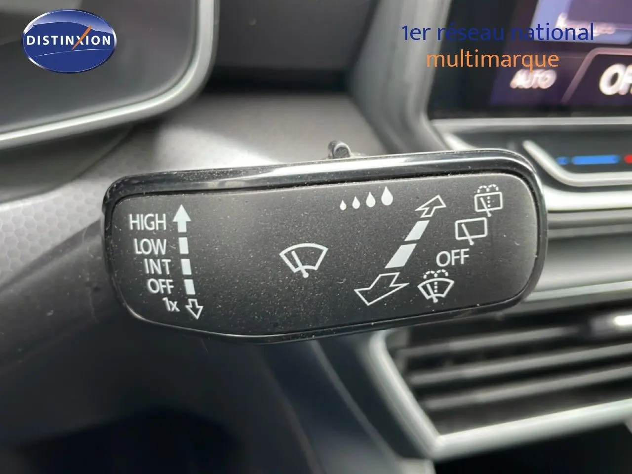 Gros plan sur la commande d’essuie-glace du SEAT Leon 2025, intérieur noir avec tableau de bord et écran partiellement visibles.