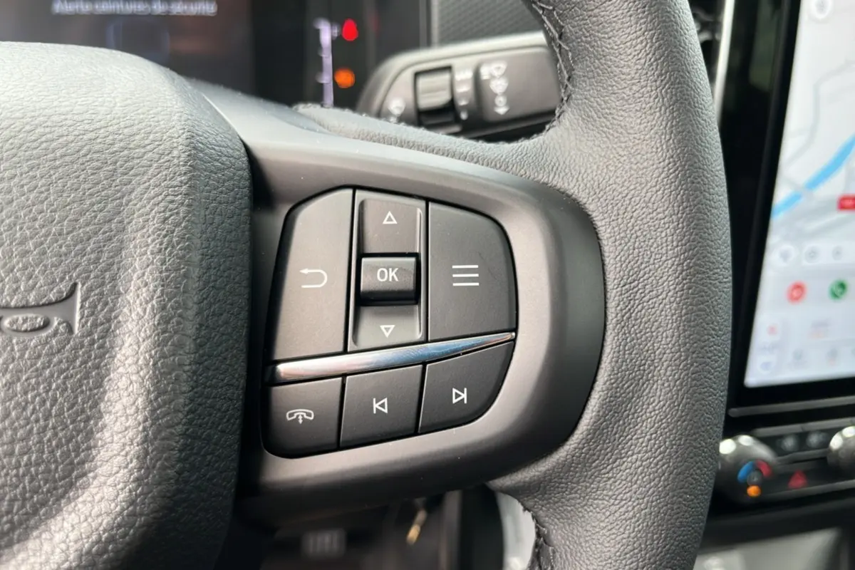Gros plan sur les commandes multifonctions à gauche du volant cuir noir du Ford Ranger gris carbone 2025.
