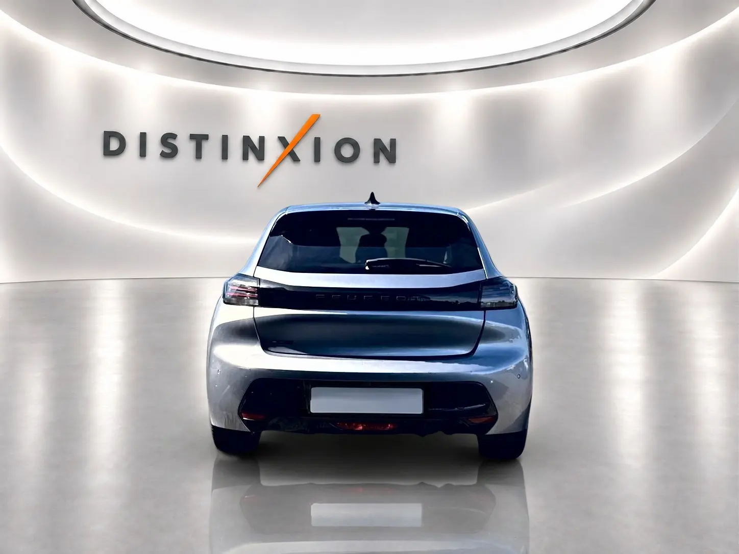 Vue arrière d'une Peugeot 208 1.2 100 Allure gris artense dans un showroom lumineux avec logo Distinxion en arrière-plan.