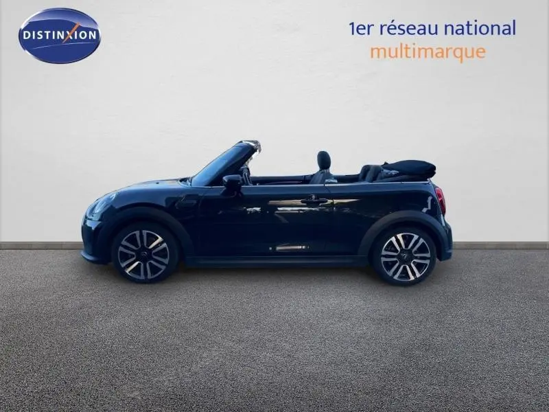 Profil droit d'une MINI Cabriolet Cooper 2023 en Midnight Black II, capote souple noire repliée, jantes alu visibles.