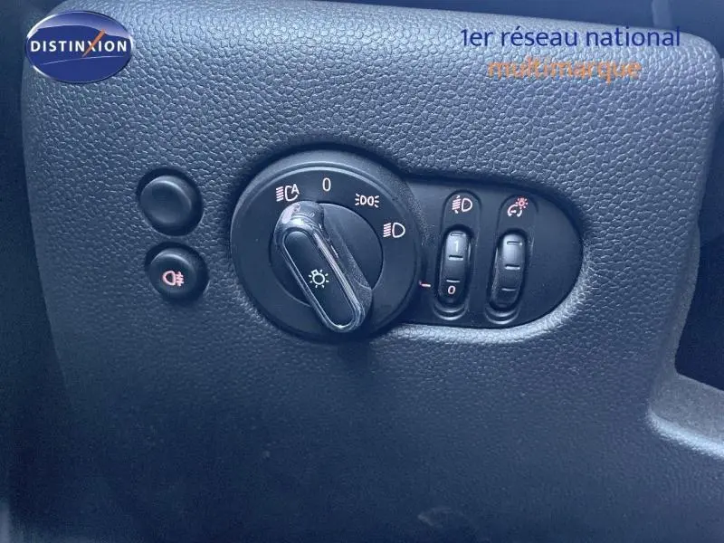 Détail du tableau de bord de la MINI Cabriolet Cooper 2023, montrant les commandes d'éclairage sur fond noir texturé.