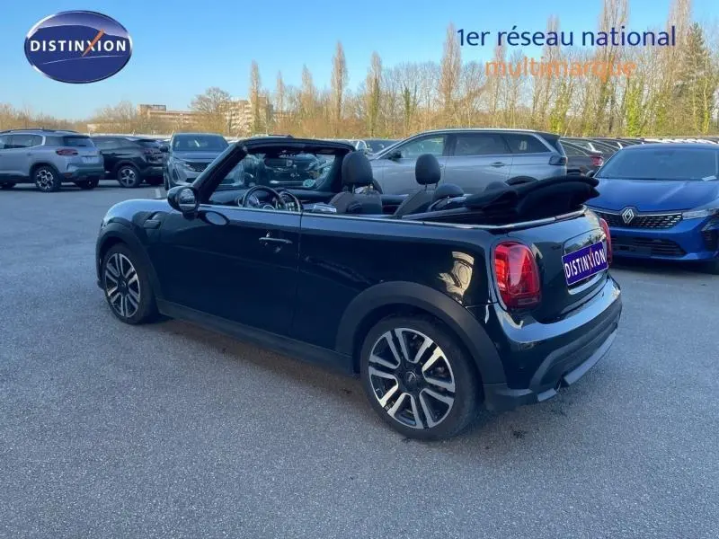 MINI Cabriolet Cooper 2023 noir Midnight Black II vue 3/4 arrière avec capote souple ouverte sur parking.
