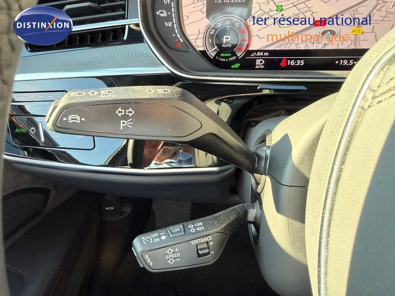 Gros plan sur les commandes au volant d'une Audi A8 noire, avec affichage numérique et fonctions d'assistance visibles.