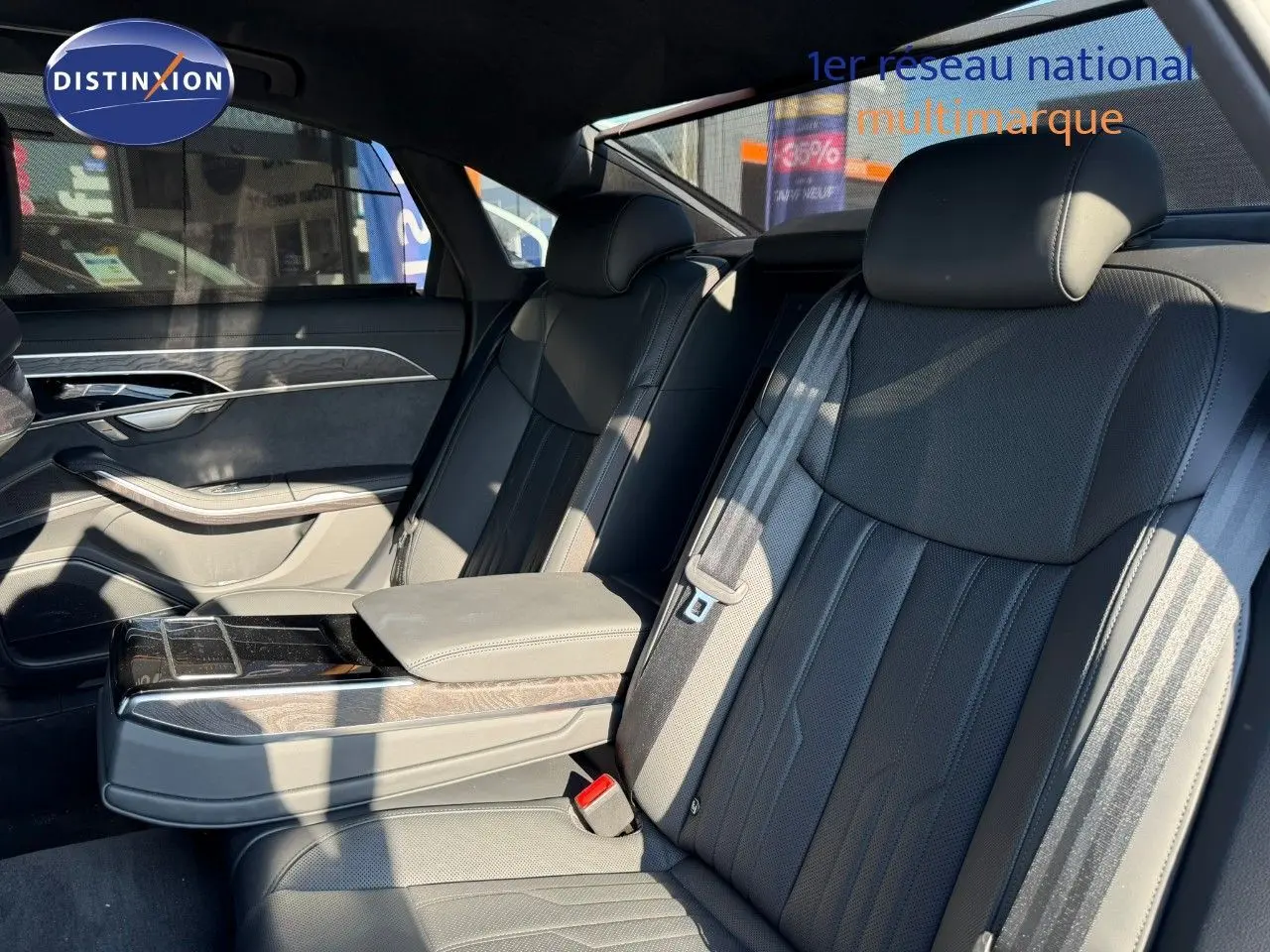 Intérieur arrière de l'Audi A8 2024 noir Sebring Cristal, sièges en cuir noir et accoudoir central avec rangement.
