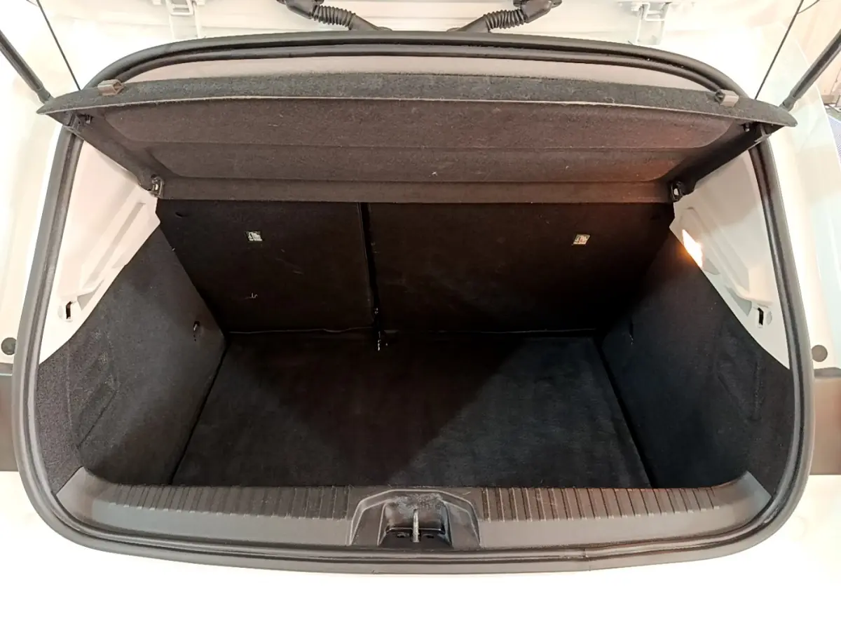Coffre ouvert vu de l'arrière d'une Renault Clio Business Blue dCi 115 blanche, intérieur noir et éclairage latéral.