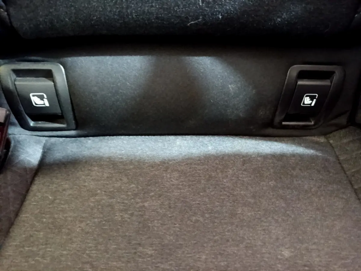 Gros plan sur les commandes de rabattement des sièges arrière dans le coffre d'une Renault Clio blanche Business Blue dCi 115.