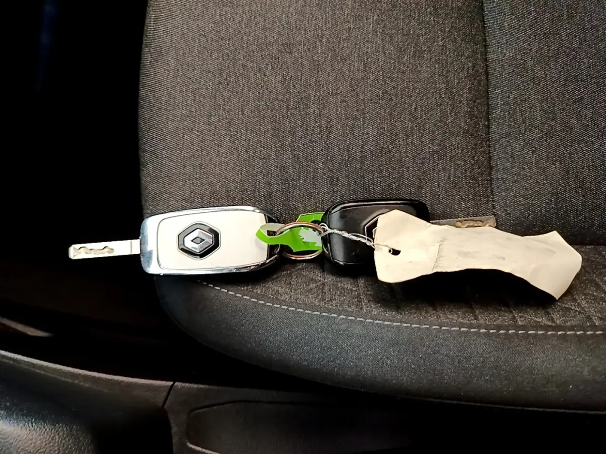 Clé de voiture Renault posée sur un siège tissu gris foncé à l'intérieur d'une Renault Clio blanche 2020.