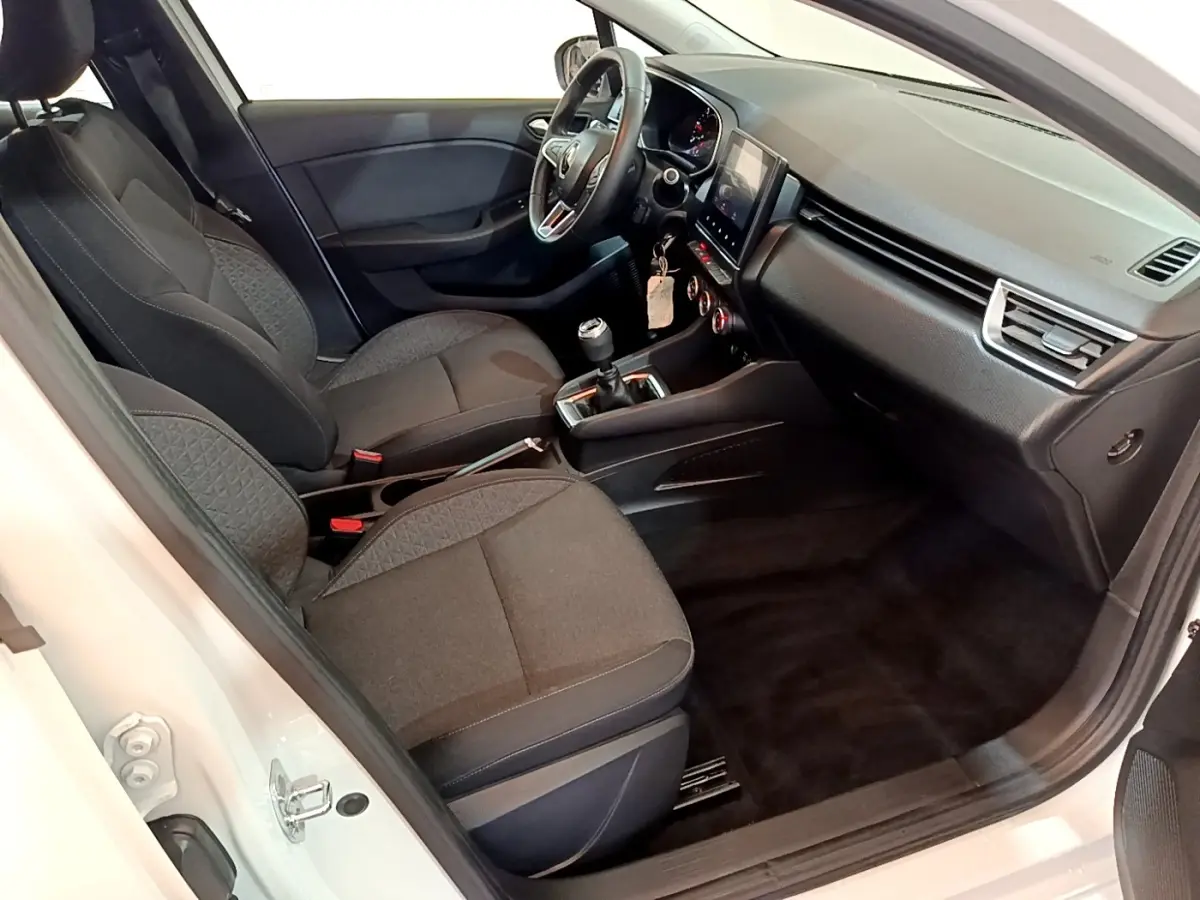 Vue intérieure côté conducteur de la Renault Clio Business Blue dCi 115 blanche, montrant sièges noirs et tableau de bord moderne.