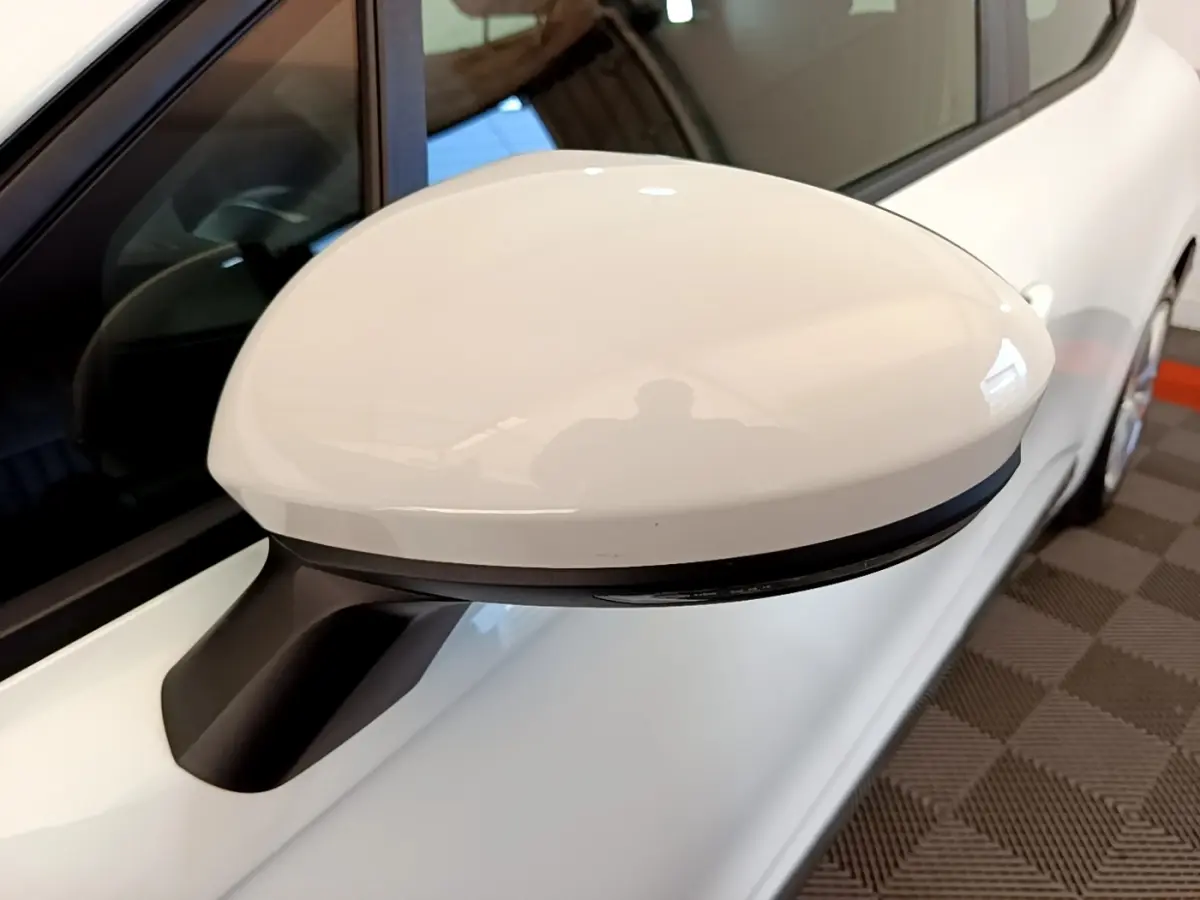 Rétroviseur blanc côté conducteur d'une Renault Clio Business Blue dCi 115 vue en gros plan sur fond intérieur.