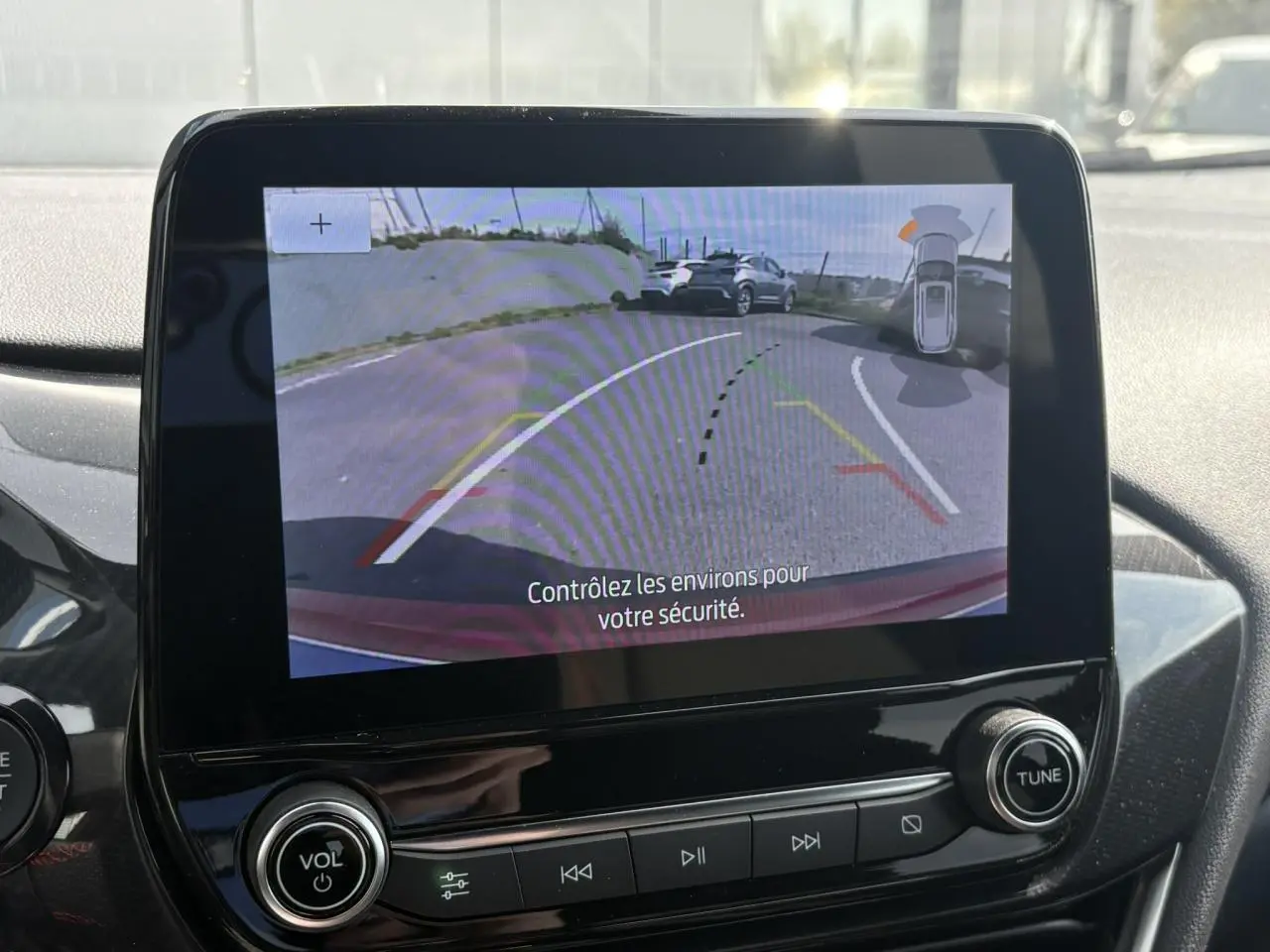Écran tactile intérieur montrant la caméra de recul 180° du Ford Puma rouge avec lignes d’aide au stationnement.
