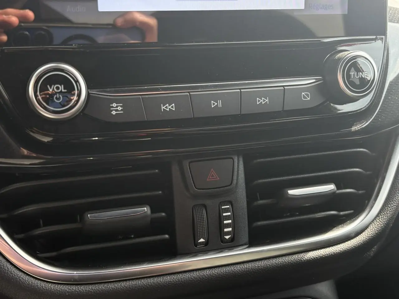 Gros plan sur la console centrale noire du Ford Puma 2023, avec commandes audio et aérateurs visibles.