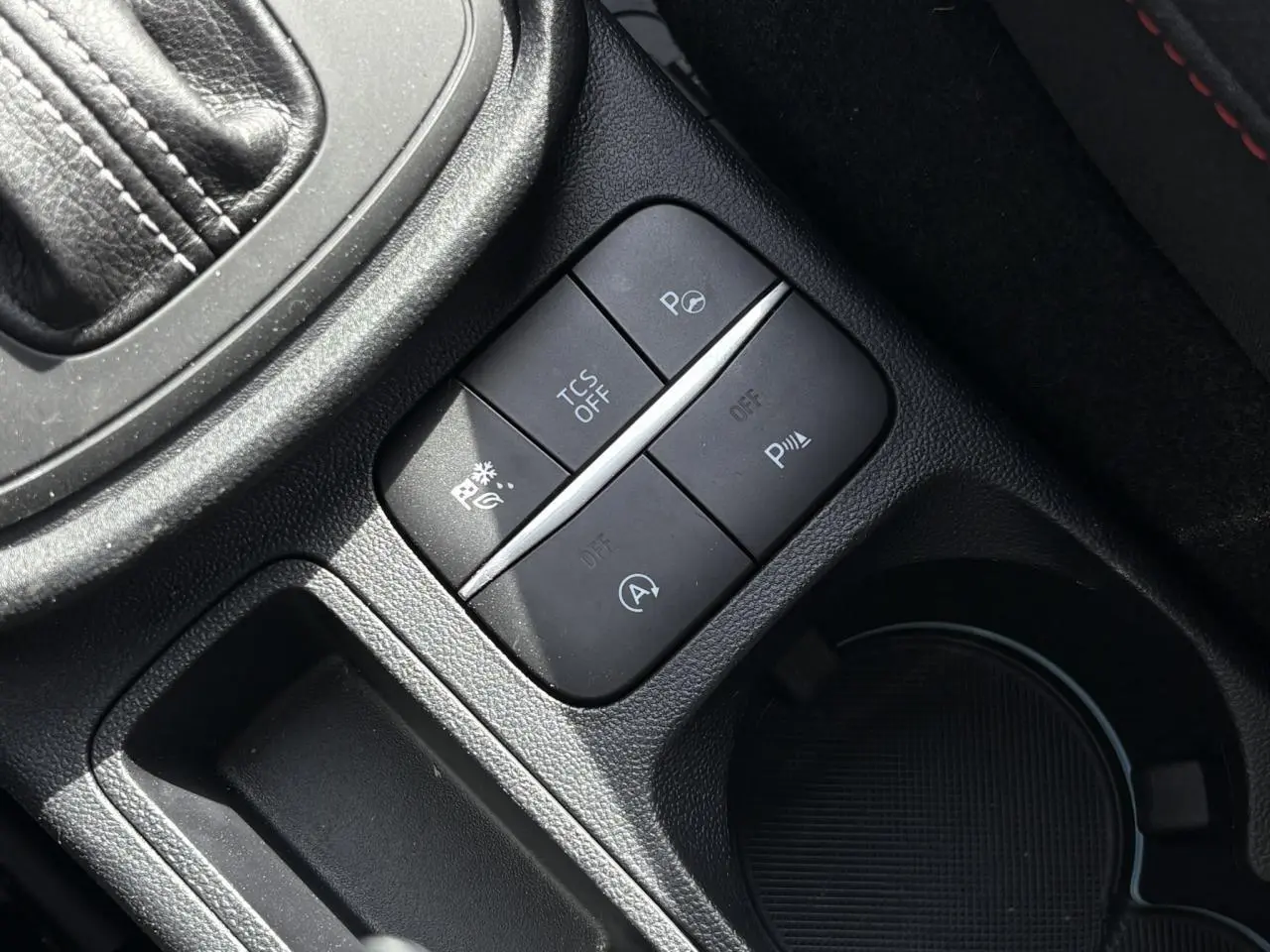 Gros plan sur les boutons de commande noirs du Ford Puma Ecoboost 155 BVA ST Line, console centrale près du levier de vitesses.