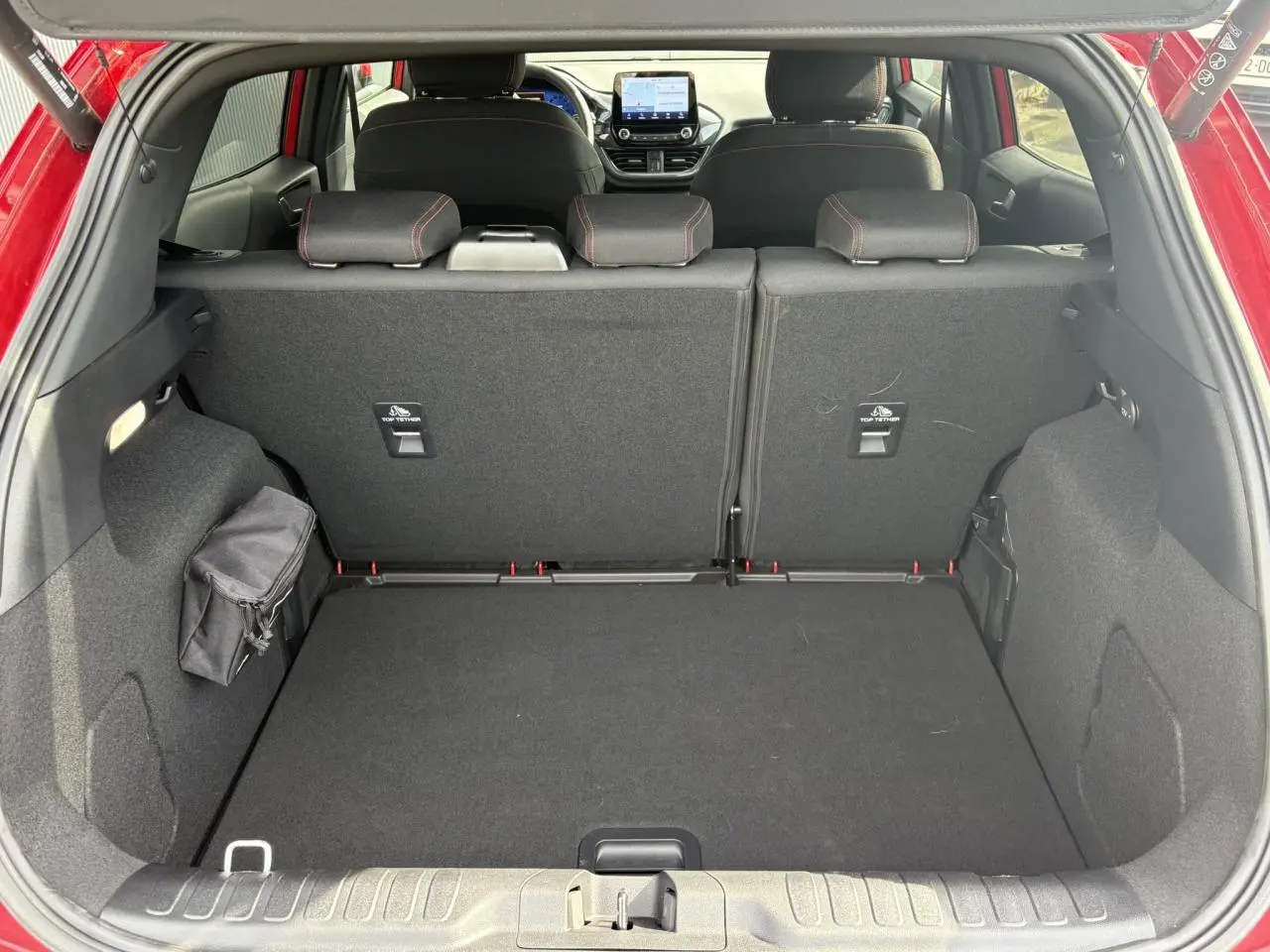 Vue arrière du coffre spacieux du Ford Puma rouge Fantastic 2023 avec sièges arrière et tableau de bord visibles.