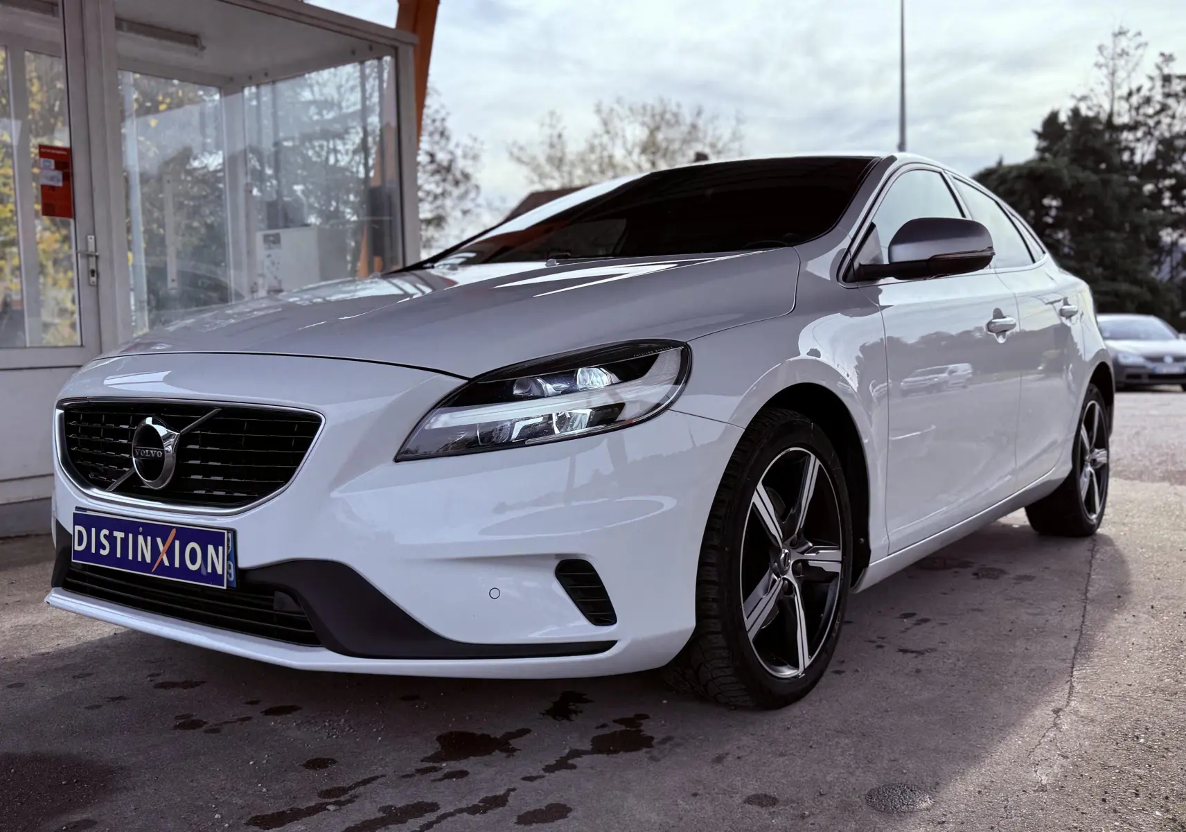 Volvo V40 R-Design blanc vue 3/4 avant droit, avec jantes alliage noires et calandre noire distinctive.