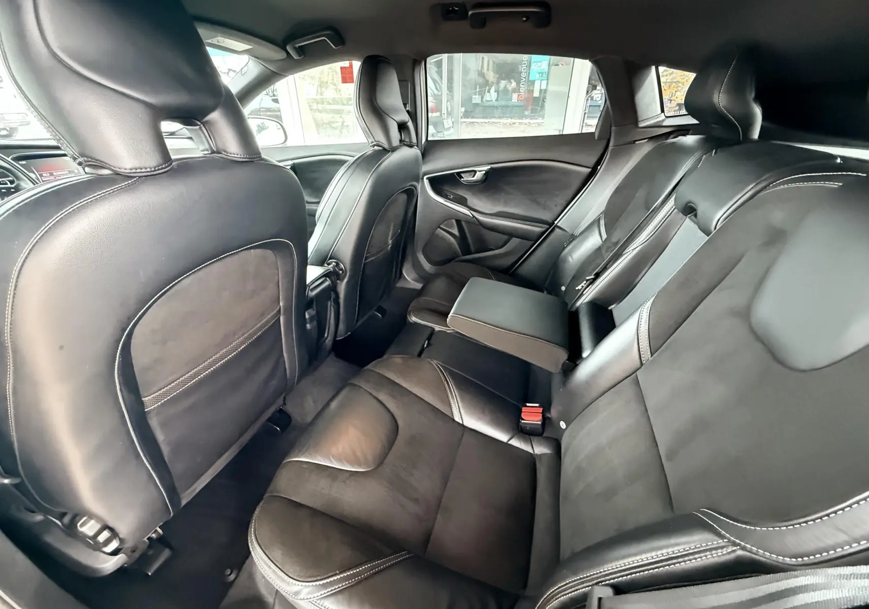 Intérieur arrière de la Volvo V40 R-Design 2017, sièges noirs en cuir avec accoudoir central déployé, vue côté droit.