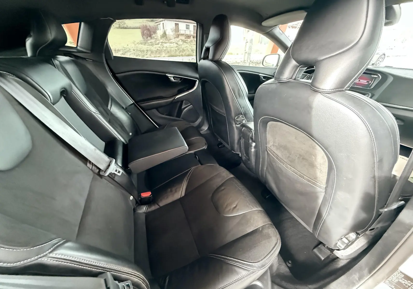 Vue intérieure arrière de la Volvo V40 R-Design 2017, sièges en cuir noir avec accoudoir central déployé.