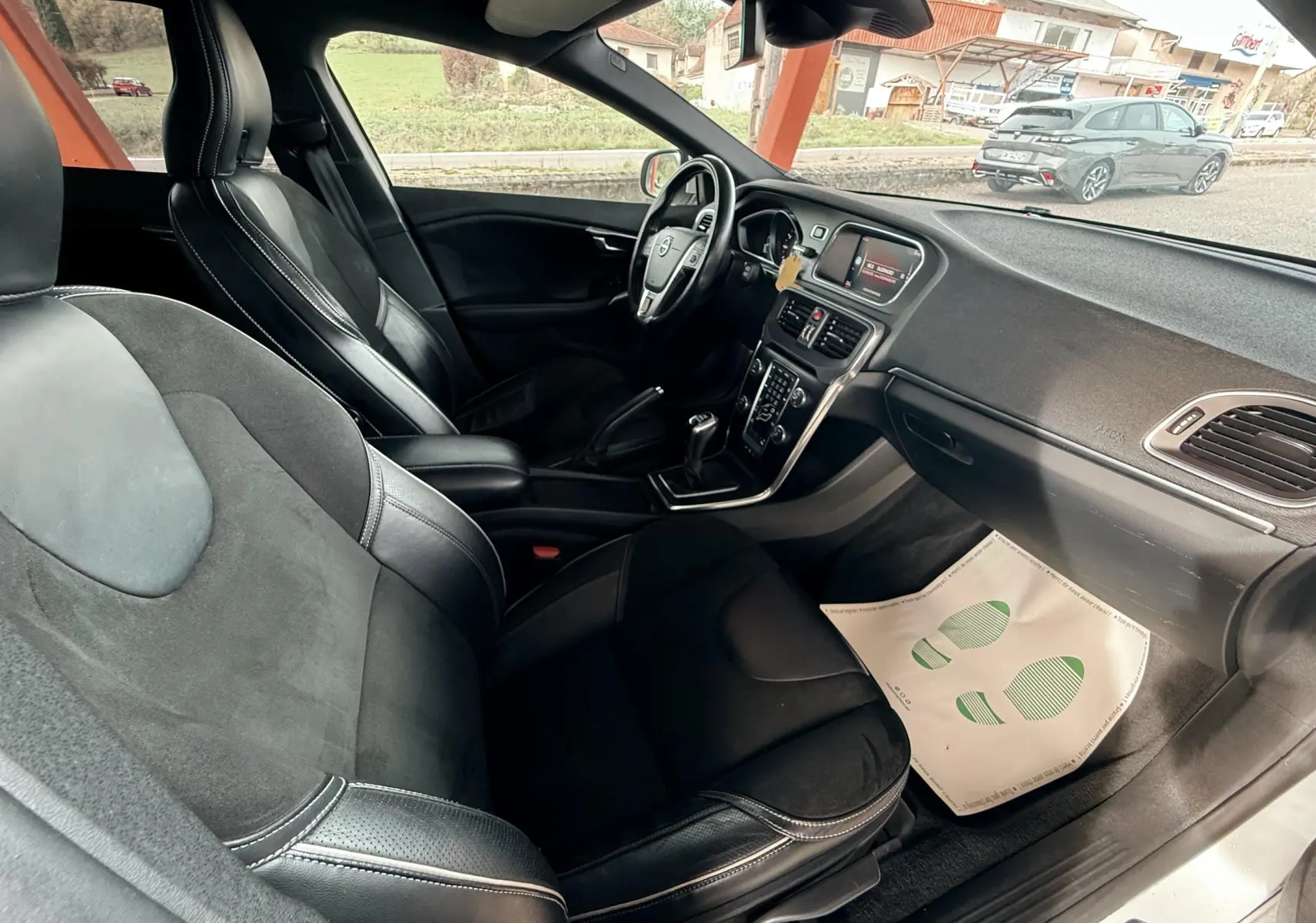 Intérieur côté passager d'une Volvo V40 R-Design 2017 avec sièges noirs en cuir et alcantara, volant et tableau de bord visibles.