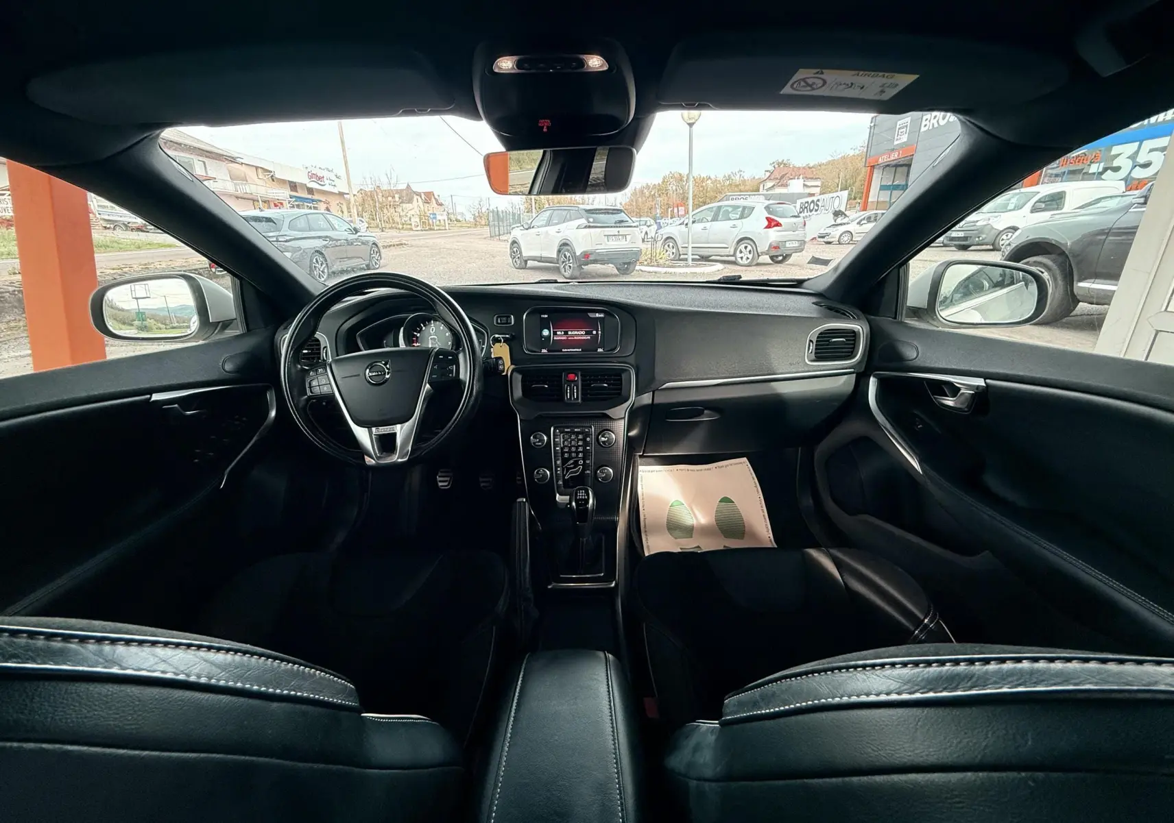 Vue intérieure avant du Volvo V40 R-Design 2017 avec tableau de bord noir et volant multifonction.