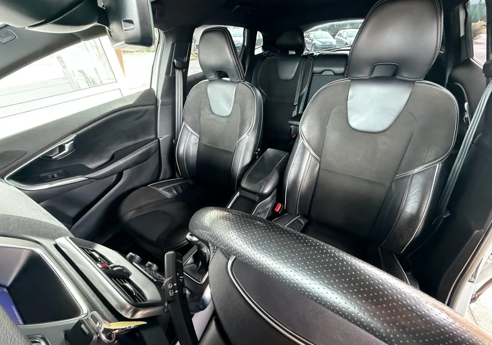 Intérieur noir de la Volvo V40 R-Design 2017, vue avant des sièges en cuir et alcantara avec volant perforé.