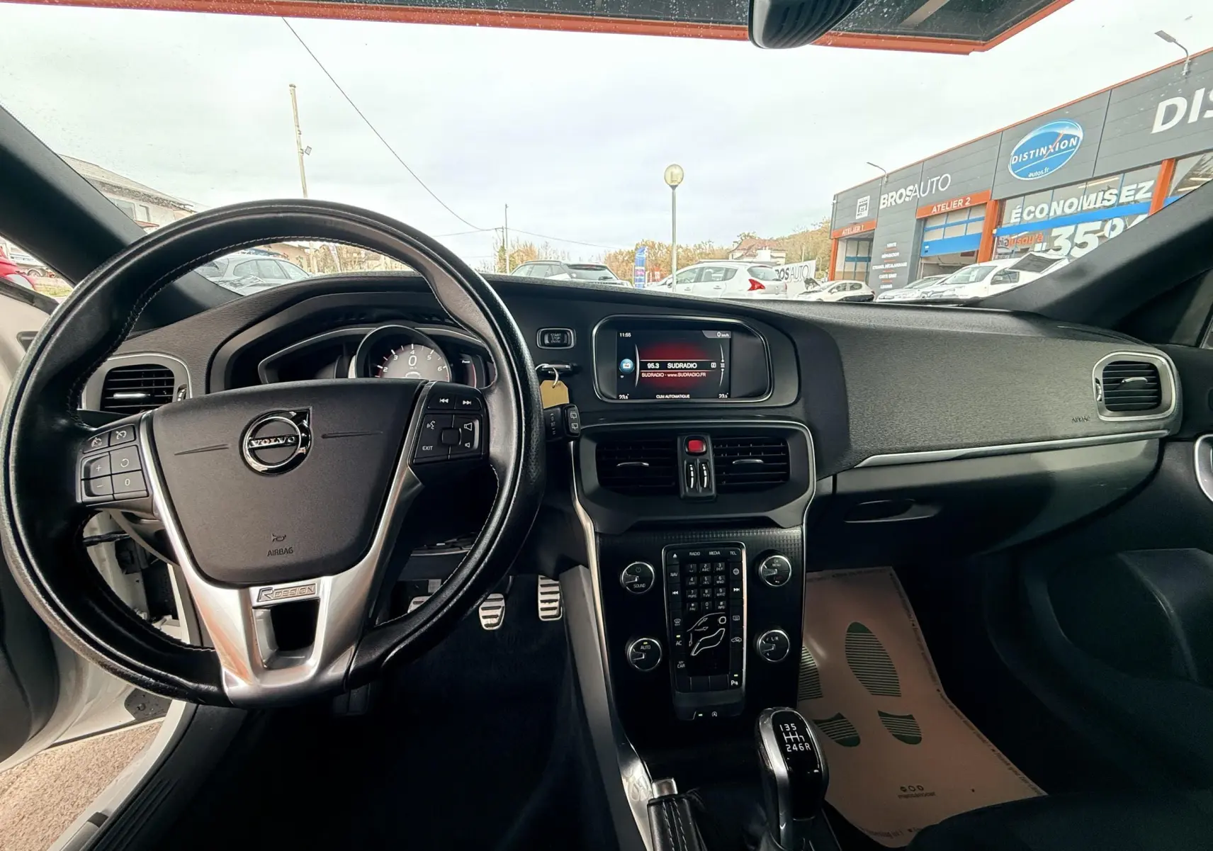 Intérieur de Volvo V40 R-Design 2017 vu côté conducteur, volant cuir noir et console centrale avec boîte manuelle.