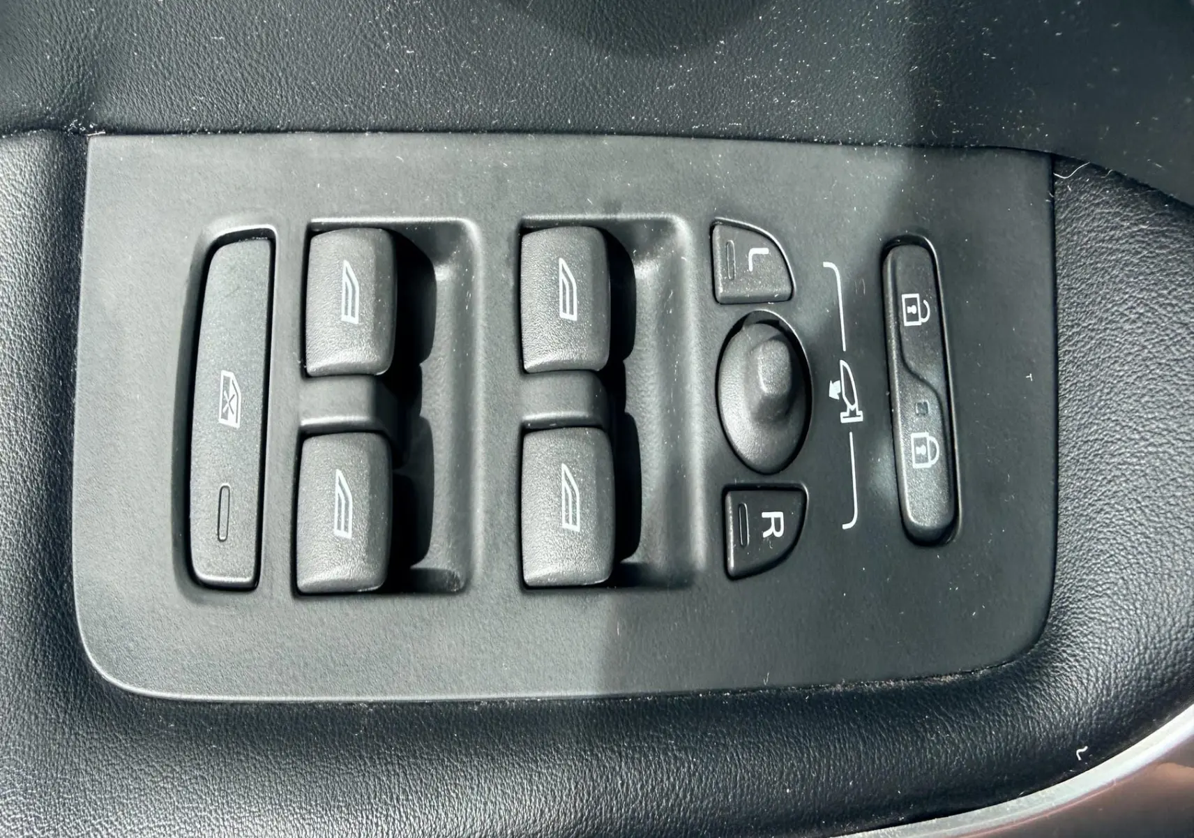 Panneau de commandes des vitres et rétroviseurs côté conducteur d'une Volvo V40 R-Design blanche, intérieur noir.