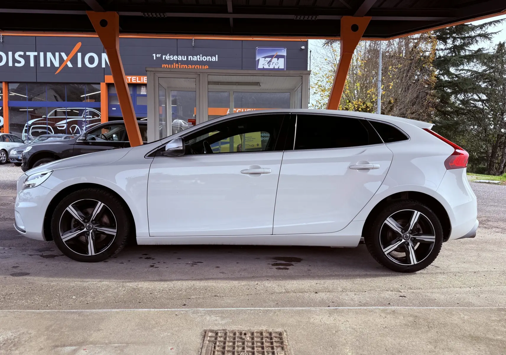 Profil côté gauche d'une Volvo V40 R-Design blanche de 2017, avec jantes alliage et vitres teintées.