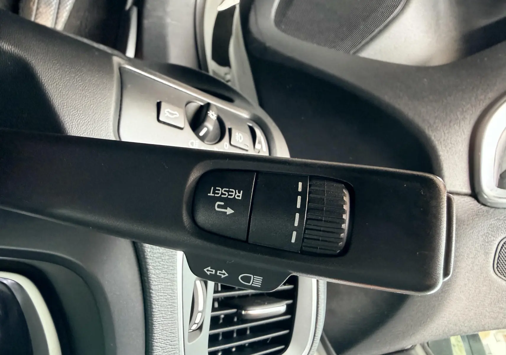 Gros plan sur la manette de clignotant avec fonction reset du Volvo V40 R-Design blanc, intérieur noir.