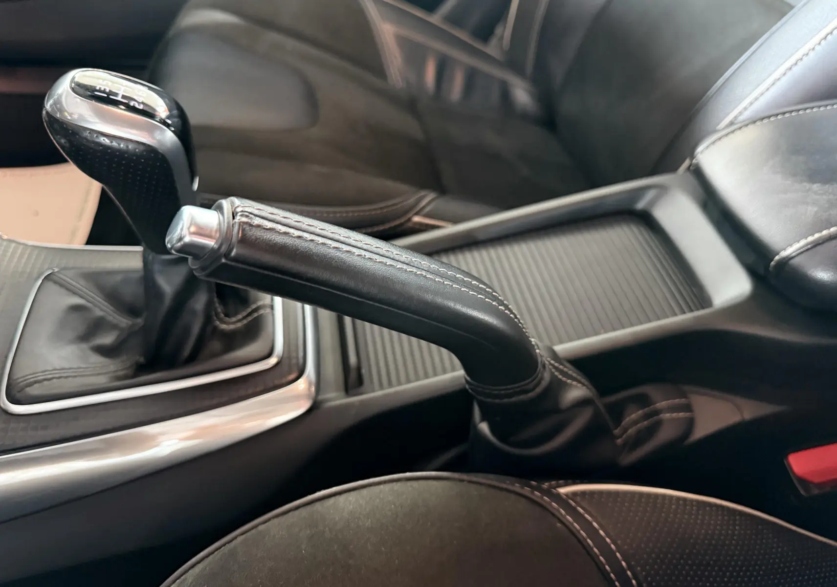 Vue rapprochée de la console centrale d'une Volvo V40 R-Design 2017, avec levier de vitesse manuel et frein à main en cuir noir.