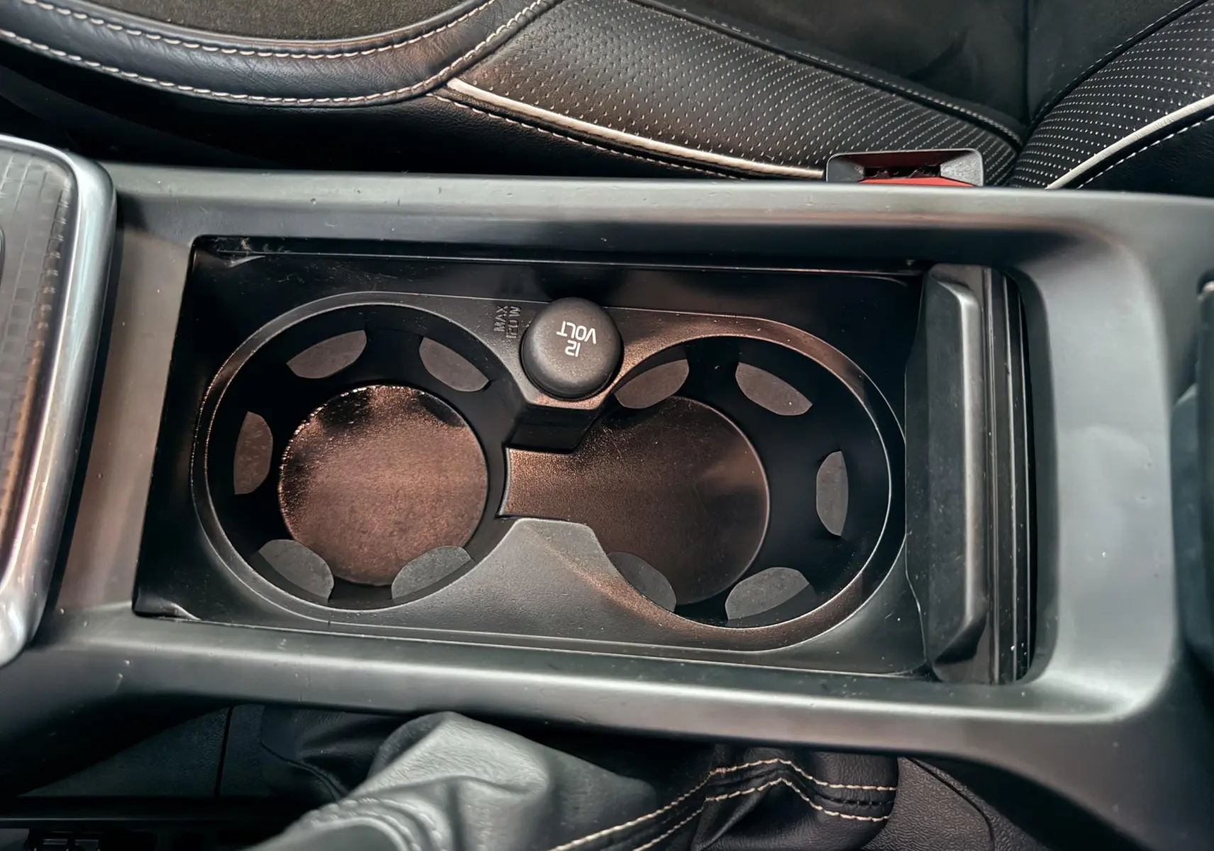 Gros plan sur les porte-gobelets noirs et la console centrale en cuir noir avec surpiqûres blanches d'une Volvo V40 R-Design blanche de 2017.