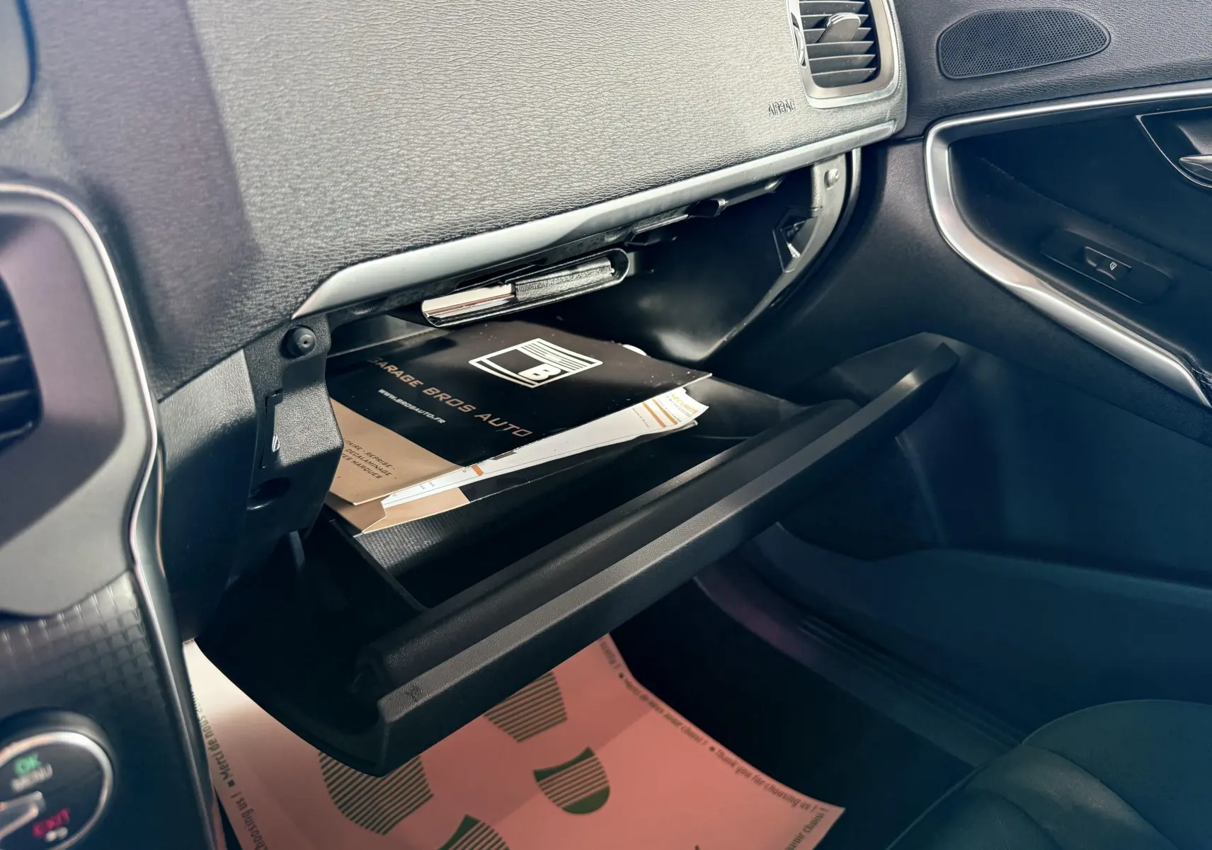 Intérieur de la Volvo V40 R-Design 2017, vue côté passager sur la boîte à gants ouverte avec documents visibles.