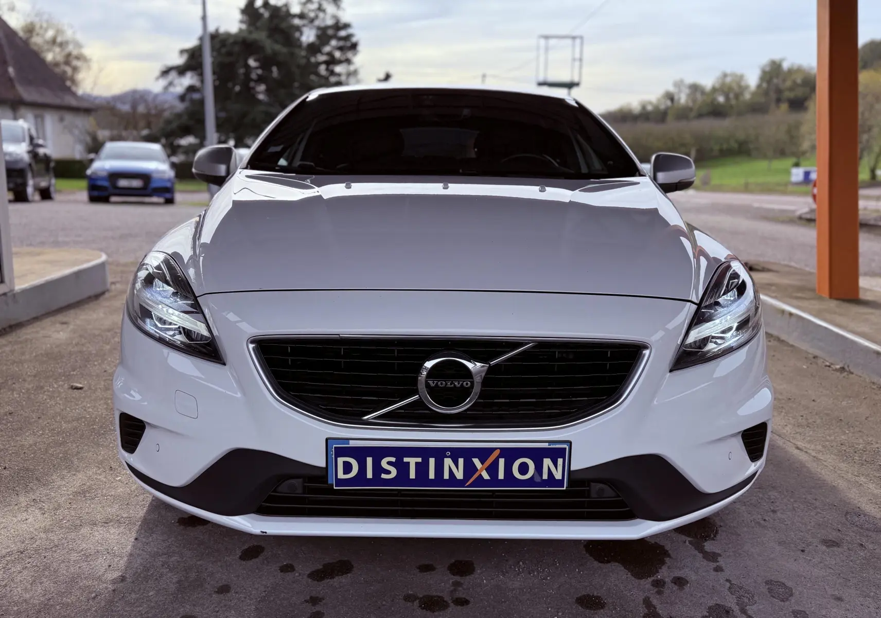 Vue frontale d'une Volvo V40 blanche 2017 avec calandre noire et plaque d'immatriculation Distinxion visible.