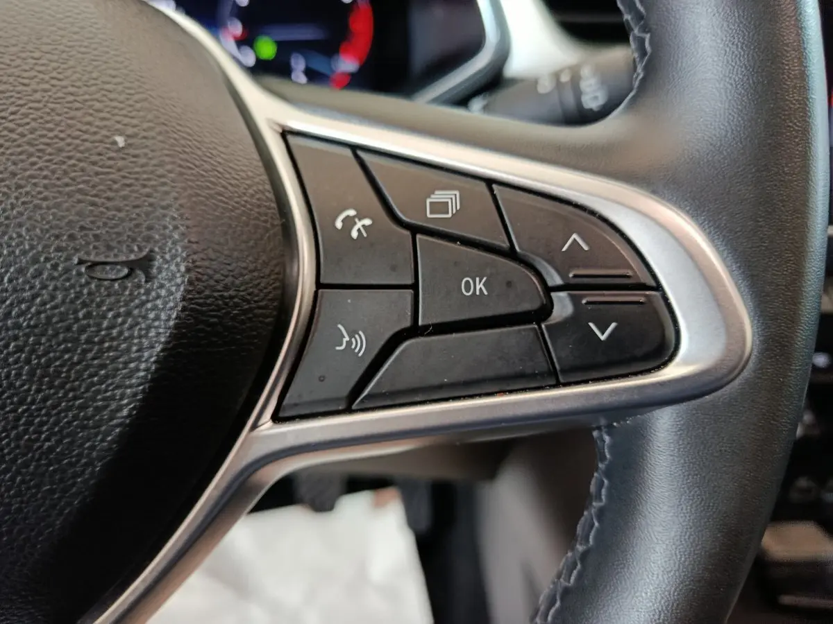 Gros plan sur les commandes multifonctions noires du volant côté gauche du Renault Captur rouge 2024.