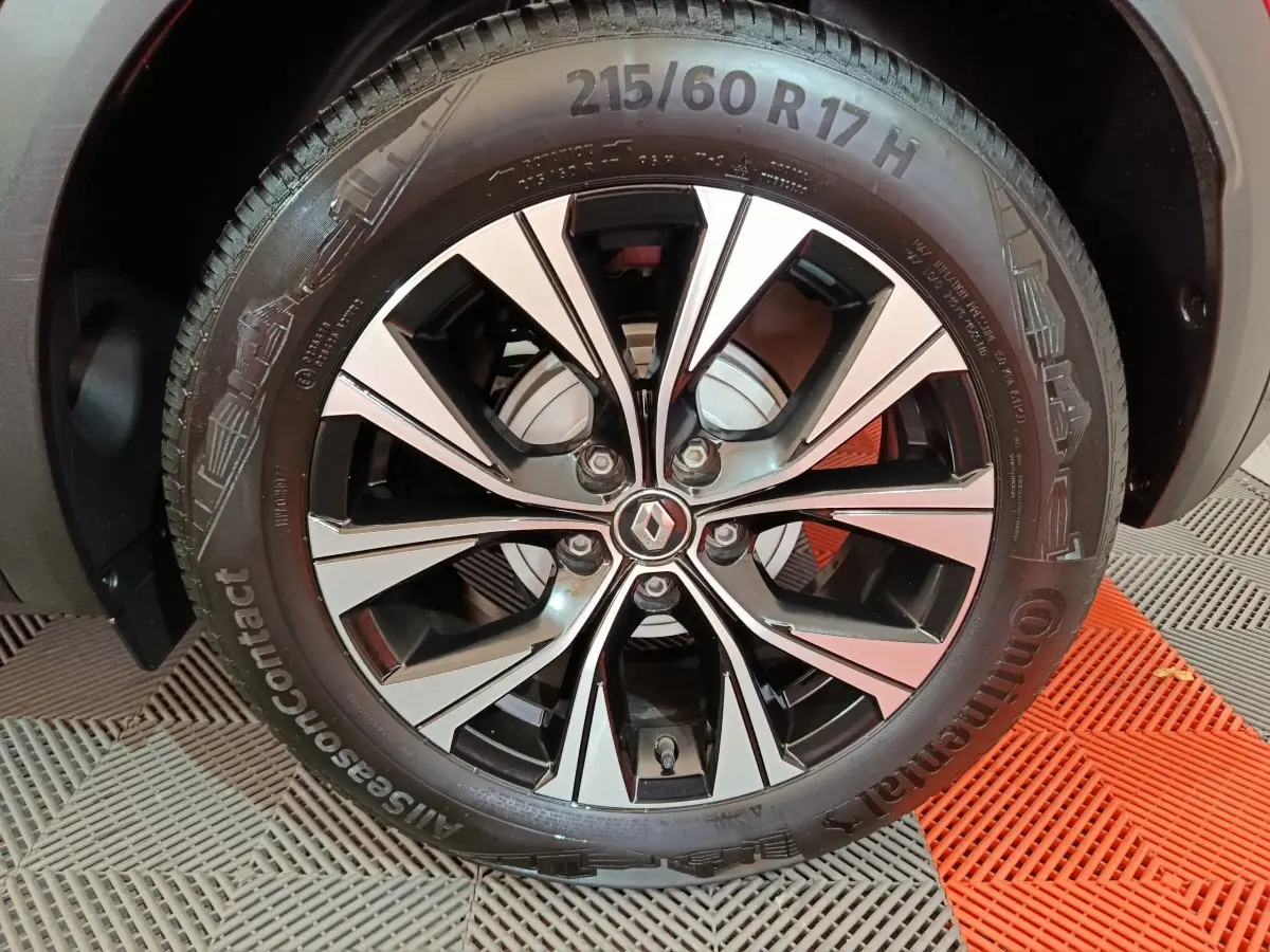 Gros plan sur la jante alliage noire et argentée avec logo Renault au centre du Renault Captur rouge 2024.