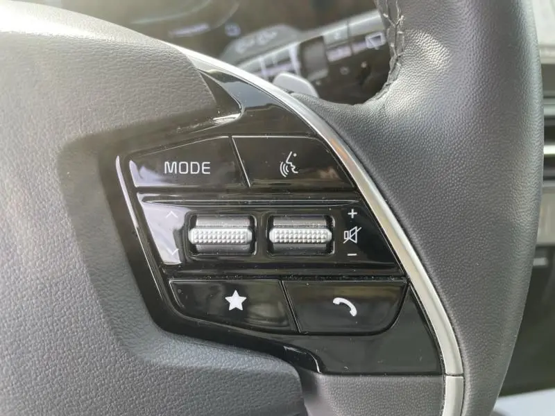 Gros plan sur les commandes multifonctions au volant du KIA Niro 2024, finition noire brillante avec boutons tactiles.
