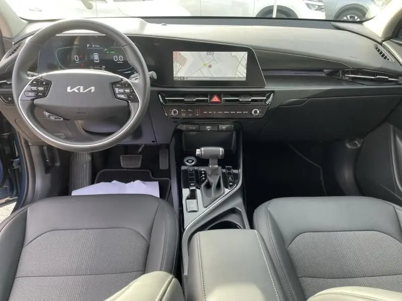 Vue intérieure avant du Kia Niro 2024 bleu métal, avec tableau de bord numérique et écran central tactile.